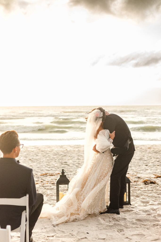 Newlyweds celebrating after their Naples beach elopement as the sun breaks through clouds